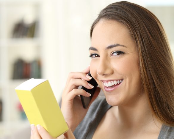 Girl calling on phone asking information about a medical product and looking at camera sitting on a couch in a house interior